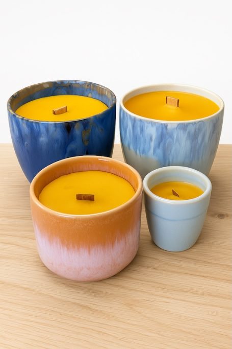 Bunte Kerzen in verschiedenen Tontöpfen, mit gelbem Wachs und Holzdochten.